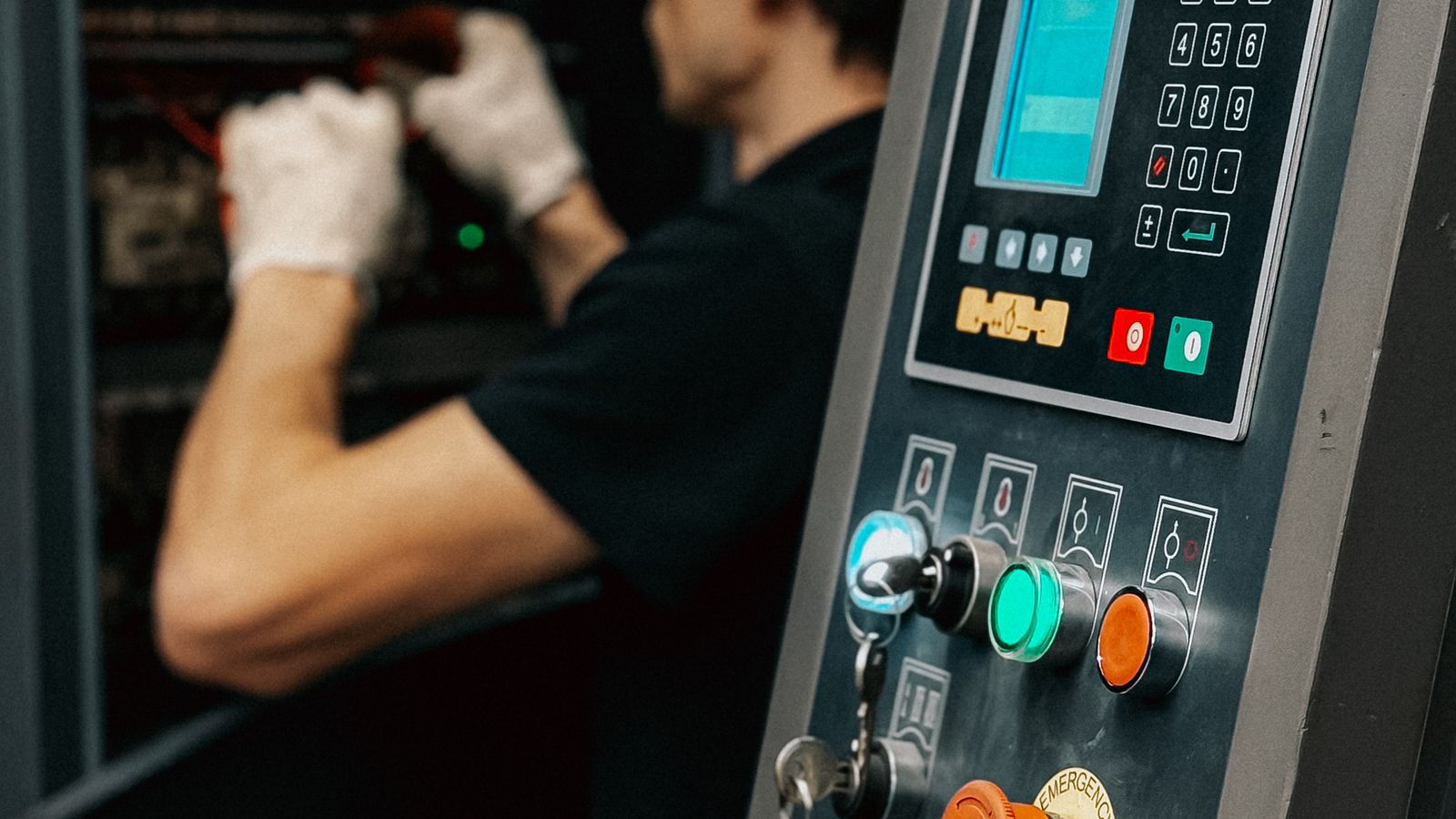 Factory technician working beside an industrial machine control panel